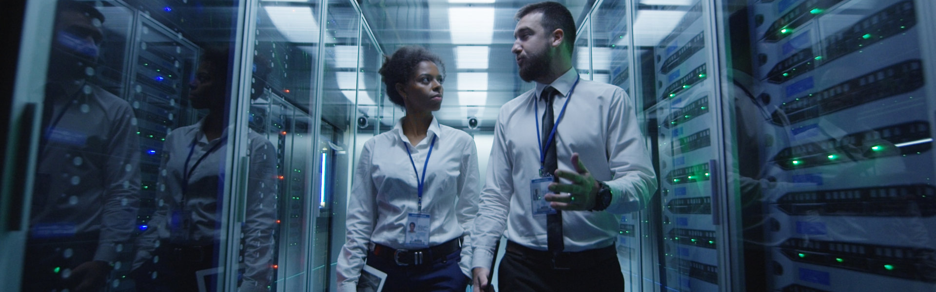 men and women walking in corridor of data center checking server hardware